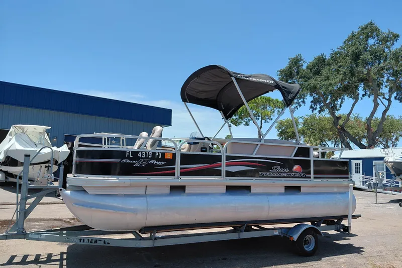 Slide: The Image of 2015 Sun Tracker Bass Buggy 18 DLX pontoon boat on trailer, parked outdoors. - 5