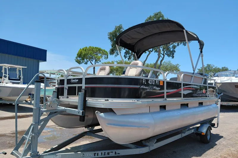 Slide: The Image of 2015 Sun Tracker Bass Buggy 18 DLX pontoon boat on trailer, outdoor setting. - 4
