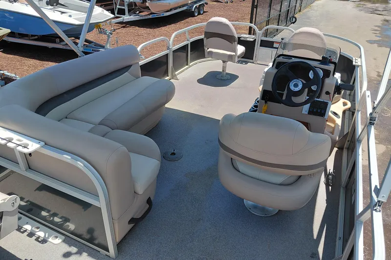 Slide: The Image of 2015 Sun Tracker Bass Buggy 18 DLX pontoon boat interior with beige seating and steering console. - 24