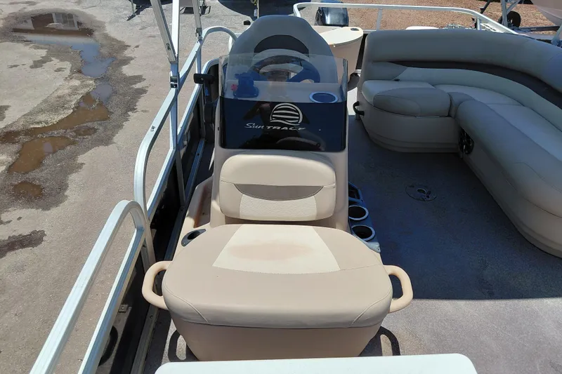 Slide: The Image of 2015 Sun Tracker Bass Buggy 18 DLX pontoon boat interior with beige seating and steering console. - 13
