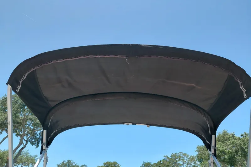 Slide: The Image of 2015 Sun Tracker Bass Buggy 18 DLX bimini top against clear blue sky. - 27