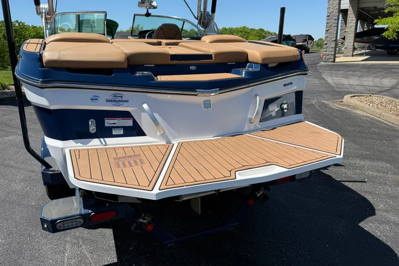Slide: The Image of 2021 MasterCraft XT21 boat with teak swim platform, parked outdoors. - 33