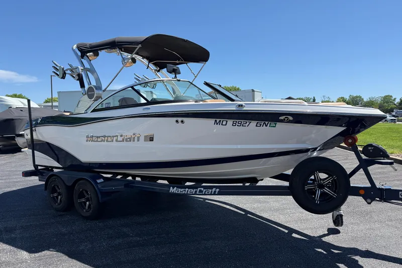 Slide: The Image of 2021 MasterCraft XT21 boat on trailer under clear blue sky. - 3