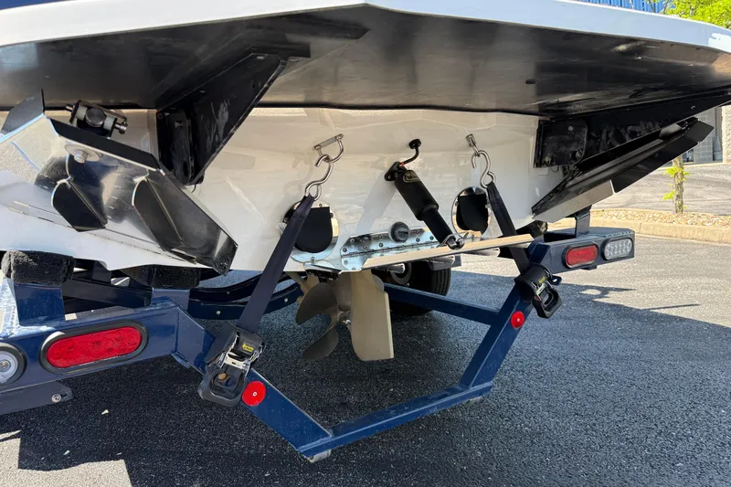 Slide: The Image of Rear view of a 2021 MasterCraft XT21 boat on a trailer, showing propeller and trim tabs. - 34