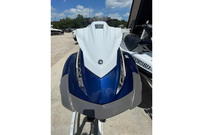 Slide: The Image of 2016 Yamaha VX-Deluxe jet ski in blue and white, parked outdoors under a sunny sky. - 2