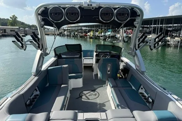 Slide: The Image of 2025 MasterCraft X24 boat interior with spacious seating, advanced audio system, and sleek design at a marina. - 14