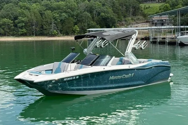 The Image of 2025 MasterCraft X24 boat on a serene lake with lush green surroundings. - 1