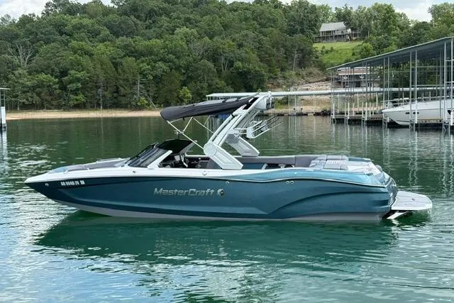 Slide: The Image of 2025 MasterCraft X24 boat on a serene lake with lush green surroundings. - 4