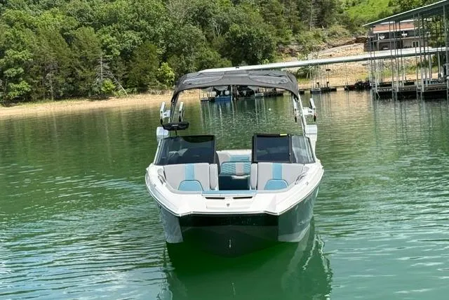Slide: The Image of 2025 MasterCraft X24 boat on a serene lake with lush green surroundings. - 5