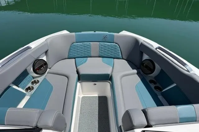 Slide: The Image of 2025 MasterCraft X24 boat interior with stylish blue and gray seating, cup holders, and speakers. - 8
