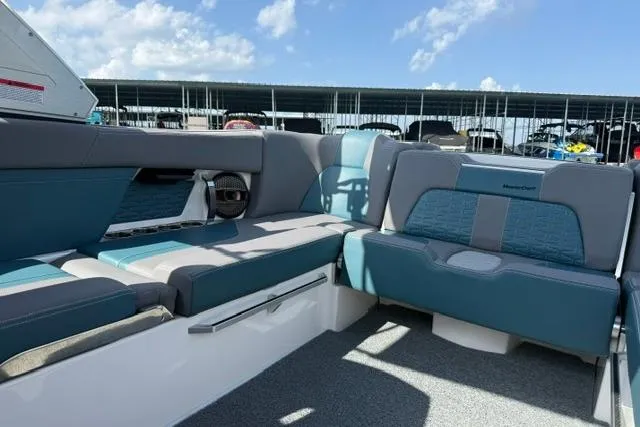 Slide: The Image of 2025 MasterCraft X24 boat interior with blue and gray seating under a sunny sky. - 11