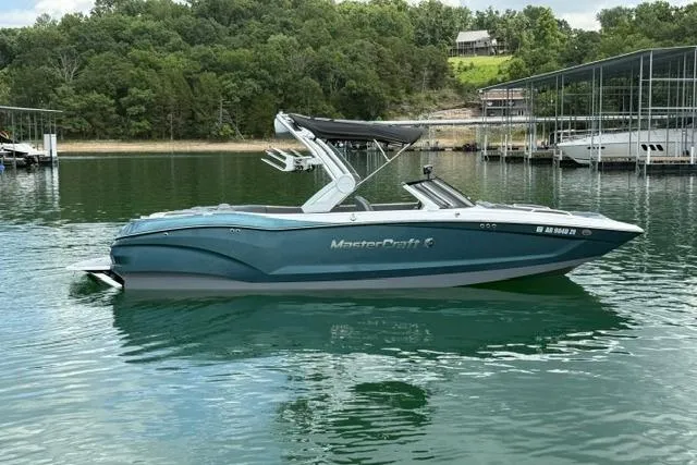 Slide: The Image of 2025 MasterCraft X24 boat on a serene lake with lush green surroundings. - 3