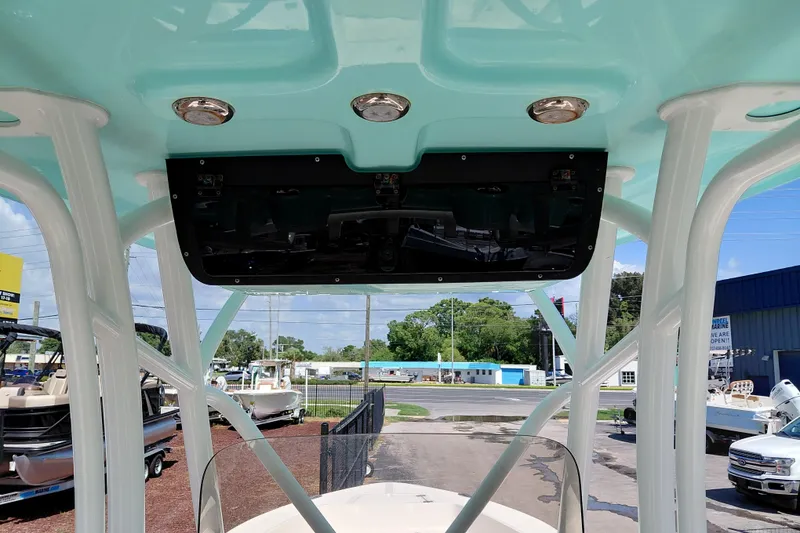 Slide: The Image of 2023 Pioneer 220 Bay Sport boat interior with teal canopy and overhead lights. - 34