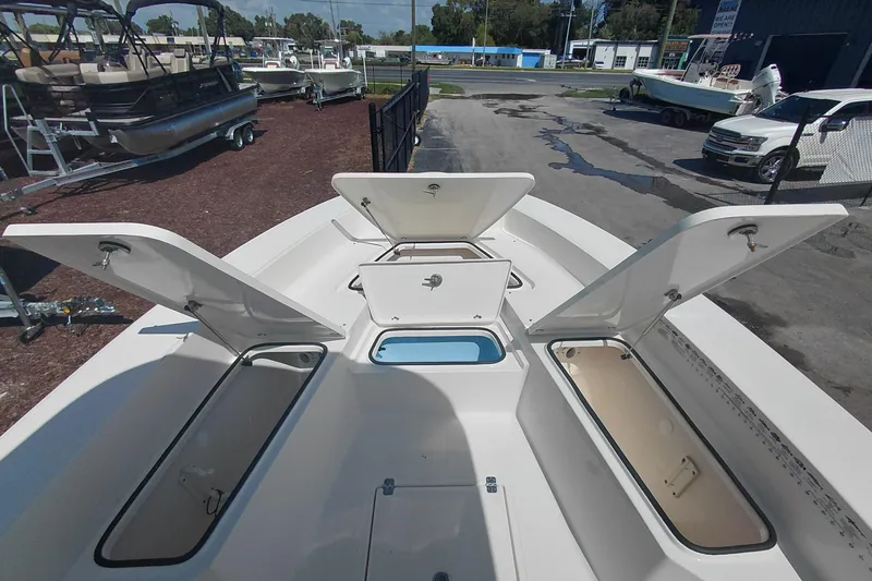 Slide: The Image of 2023 Pioneer 220 Bay Sport boat with open storage compartments, displayed outdoors. - 17