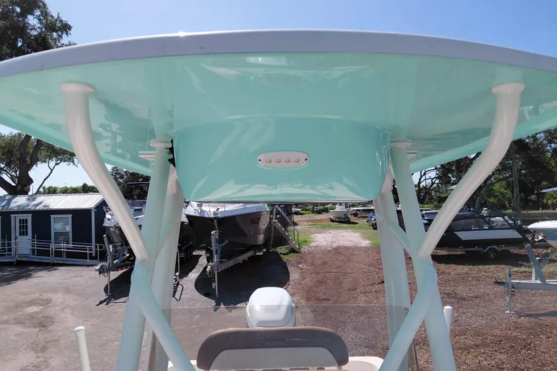 Slide: The Image of 2023 Pioneer 220 Bay Sport boat with teal T-top, parked outdoors. - 29