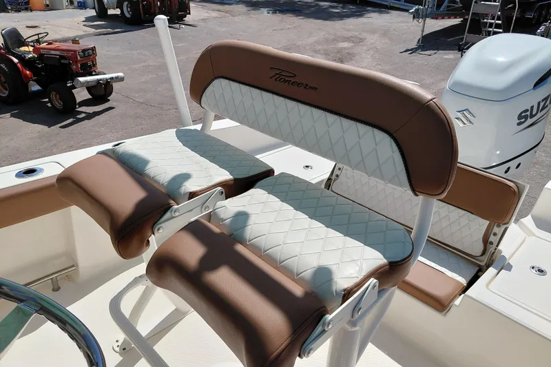 Slide: The Image of 2023 Pioneer 220 Bay Sport boat seating with brown and white upholstery, Suzuki engine visible. - 38