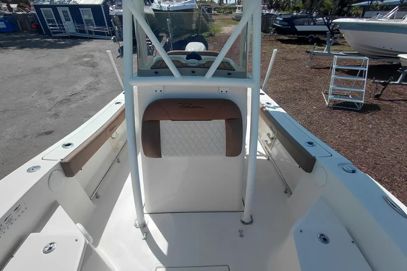 Slide: The Image of 2023 Pioneer 220 Bay Sport boat interior with seating and console, parked outdoors. - 24