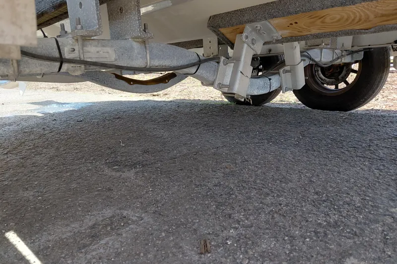 Slide: The Image of Underneath view of a 2023 Pioneer 220 Bay Sport trailer, showcasing suspension and wheel details. - 64