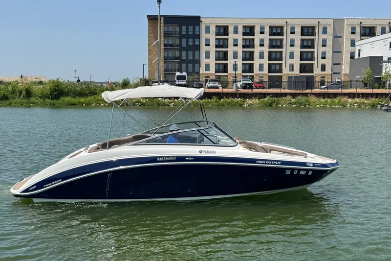 Slide: The Image of 2011 Yamaha Boats 242 Limited on water, near modern buildings, under clear sky. - 4