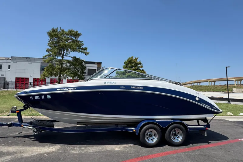 Slide: The Image of 2011 Yamaha Boats 242 Limited on trailer, parked outdoors under clear blue sky. - 23