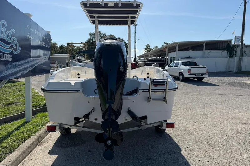Slide: The Image of 2025 Bayliner Trophy T18 boat with outboard motor, parked at a marina under clear skies. - 30