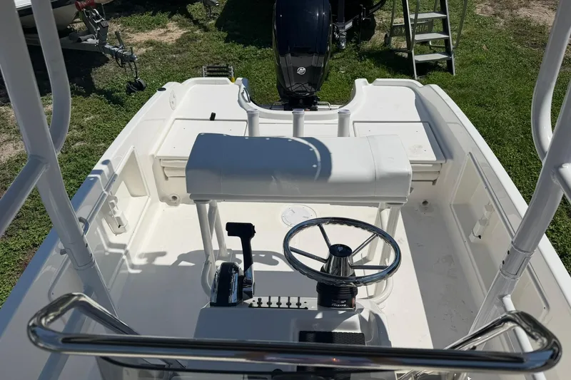 Slide: The Image of 2025 Bayliner Trophy T18 boat interior with steering wheel and controls, parked on grass. - 8