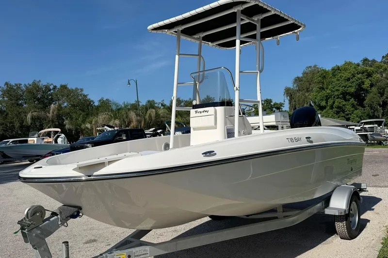 Slide: The Image of 2025 Bayliner Trophy T18 boat on trailer, parked outdoors under clear sky. - 2