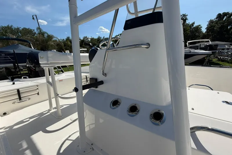Slide: The Image of 2025 Bayliner Trophy T18 boat interior with rod holders and seating, under clear blue sky. - 17