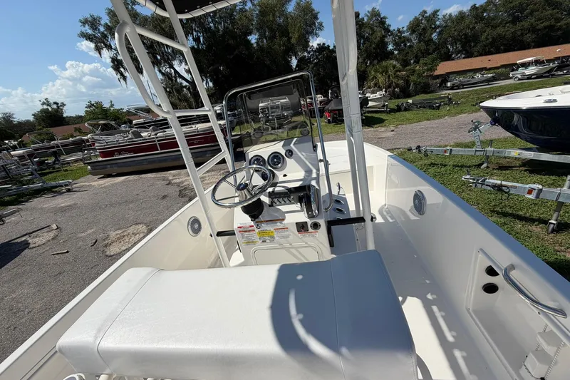 Slide: The Image of 2025 Bayliner Trophy T18 boat interior with steering wheel and seating, parked outdoors. - 7