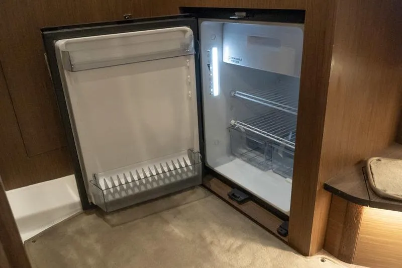 Slide: The Image of Open refrigerator inside 2026 Beneteau Antares 11 Coupe, showcasing interior shelves and lighting. - 24