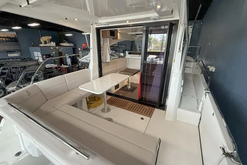 Slide: The Image of 2026 Beneteau Antares 11 Coupe interior with seating and table in a showroom. - 7