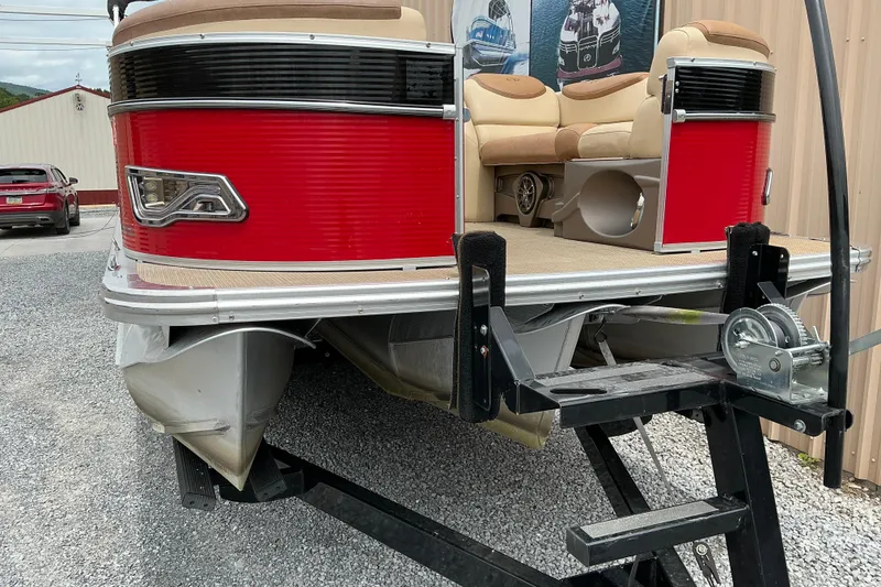Slide: The Image of 2019 Avalon Catalina Quad Lounge pontoon boat on trailer, featuring red exterior and beige seating. - 1