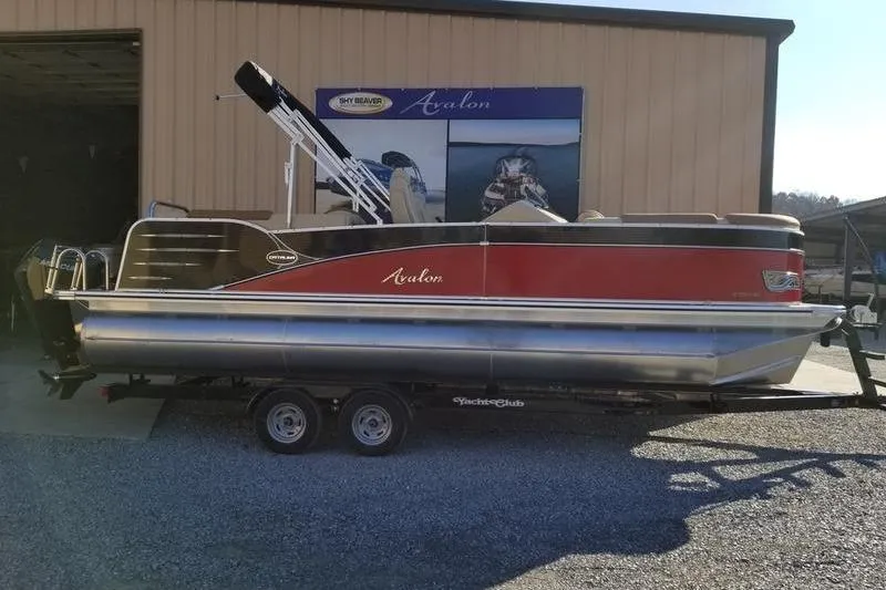 The Image of 2019 Avalon Catalina Quad Lounge 23' pontoon boat on trailer outside a building. - 0