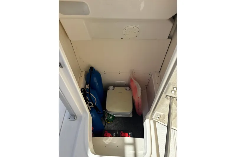 Slide: The Image of 2019 Robalo R242 Center Console storage area with marine equipment and portable toilet. - 27