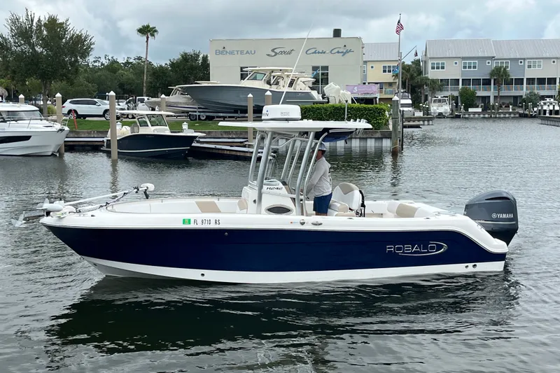 Slide: The Image of 2019 Robalo R242 Center Console boat on water, featuring Yamaha engine, dockside view. - 7
