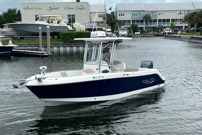 Slide: The Image of 2019 Robalo R242 Center Console boat cruising in a marina with waterfront buildings. - 8