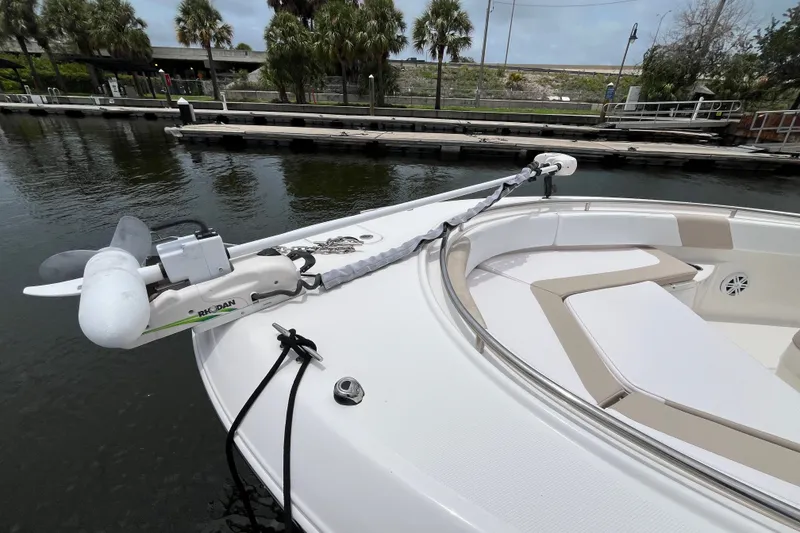 Slide: The Image of 2019 Robalo R242 Center Console boat with trolling motor docked by water. - 12