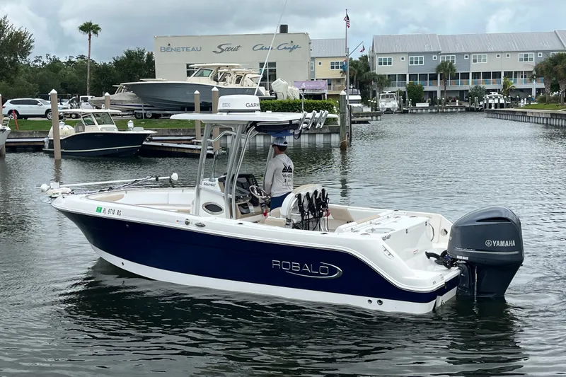 Slide: The Image of 2019 Robalo R242 Center Console boat with Yamaha engine in a marina setting. - 6