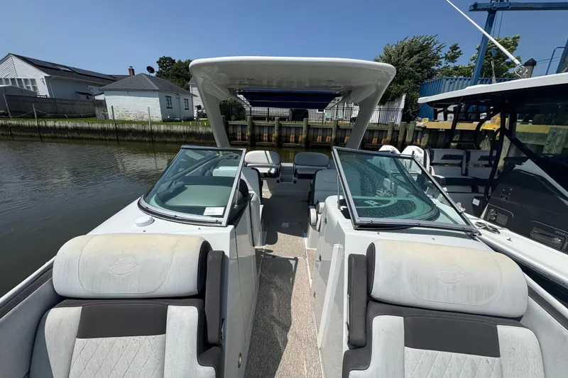 Slide: The Image of 2018 Crownline Eclipse E30 boat interior with dual windshields and seating, docked by a canal. - 21