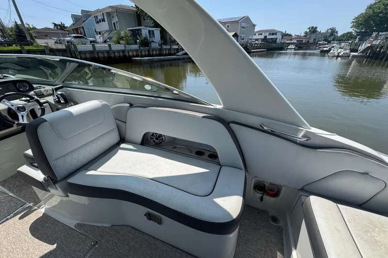 Slide: The Image of 2018 Crownline Eclipse E30 boat interior with seating and steering wheel, docked by waterfront homes. - 7