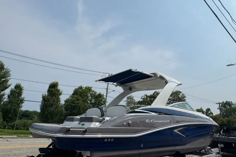 Slide: The Image of 2018 Crownline Eclipse E30 boat with sleek design on a trailer, under a clear sky. - 1