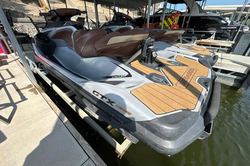 Slide: The Image of 2018 Sea-Doo GTX Limited 230 jet ski docked, featuring sleek design and brown seating. - 3