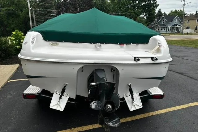 Slide: The Image of 1999 Chris-Craft 200 Bowrider SS with green cover, parked on asphalt. - 31