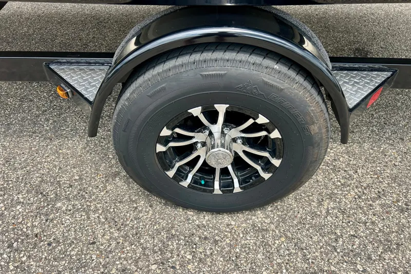 Slide: The Image of 2023 Starcraft SVX 211 IO trailer wheel with black alloy rim on asphalt. - 19