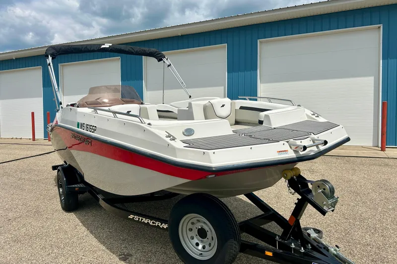 Slide: The Image of 2023 Starcraft SVX 211 IO boat on trailer, parked outside blue building. - 3