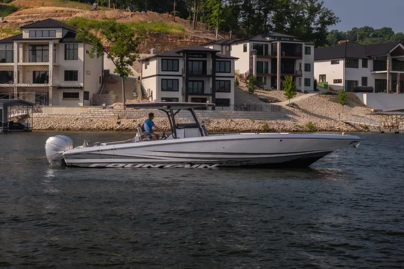 Slide: The Image of 2022 Fountain 38 SC boat cruising near modern waterfront homes. - 7