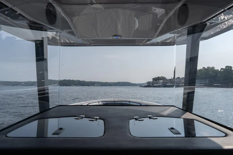 Slide: The Image of 2022 Fountain 38 SC boat interior view, navigating a serene lake with distant shoreline. - 19