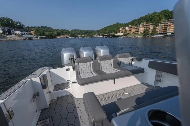 Slide: The Image of 2022 Fountain 38 SC boat interior with seating, on a scenic lake backdrop. - 23