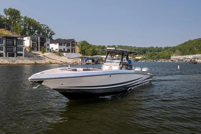 Slide: The Image of 2022 Fountain 38 SC boat cruising on a scenic lake near modern waterfront homes. - 6
