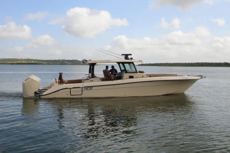 Slide: The Image of 2024 HCB 42 Lujo boat cruising on calm water with passengers and a dog. - 100